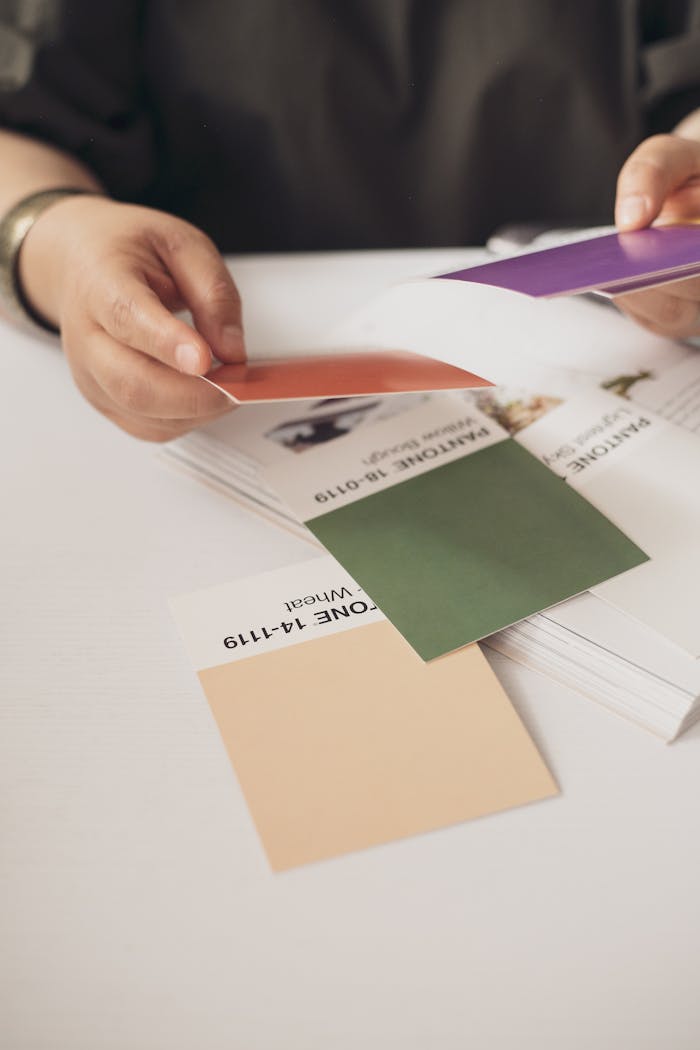 Close-up of hands selecting Pantone color swatches in a creative setting.